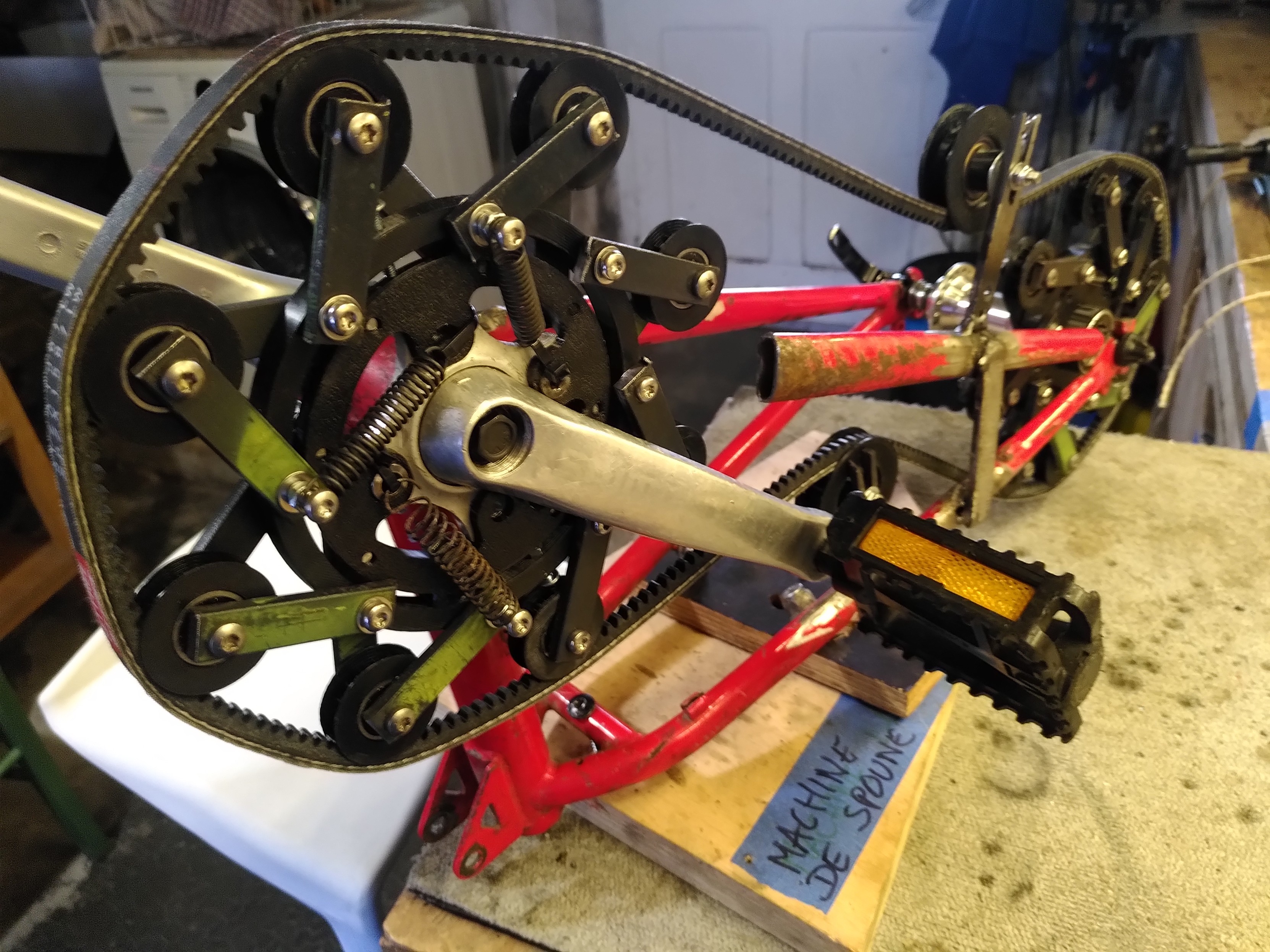 Une valise en bois peinte en rouge, avec une charnière sur le dessus. Sur les grandes faces, deux trous évidés avec des filtres en papier dedans, et trois trous avec des ventilateurs et une grille devant. Une prise électrique sur secteur pour l'alimenter est posée à côté